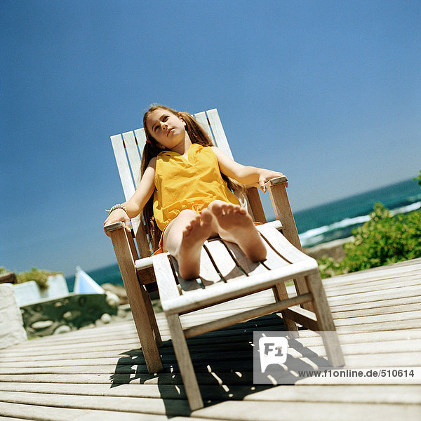 Mädchen sitzend im Liegestuhl  Meer im Hintergrund