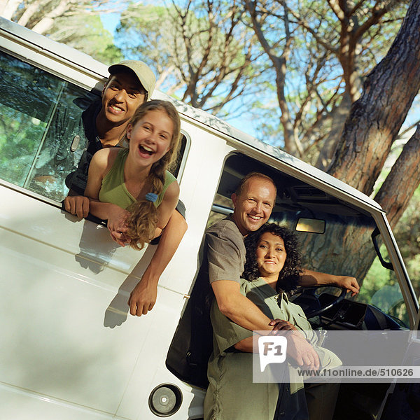 Family portrait  children sticking heads out of van window  parents in open door of van