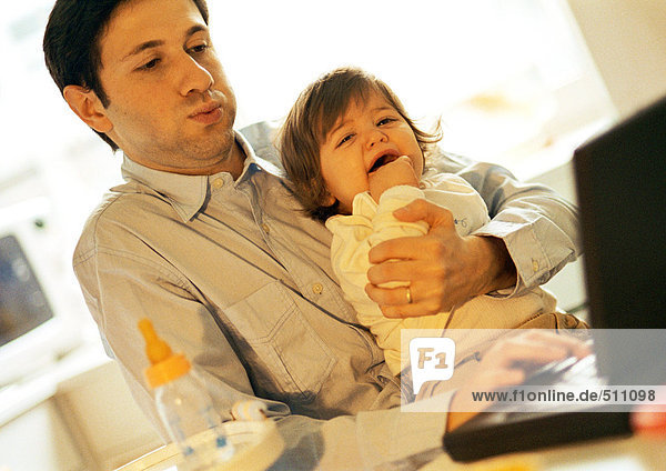 Vater und Baby  Vater mit Laptop  Baby weinen