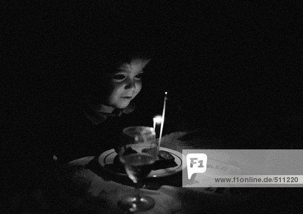 Kind sitzend am kerzenbeleuchteten Tisch  s/w.