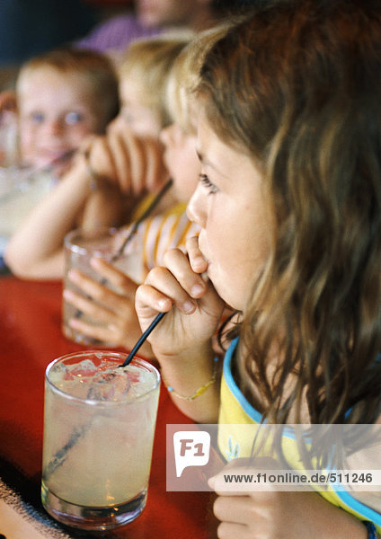 Kinder  die durch Strohhalme trinken.