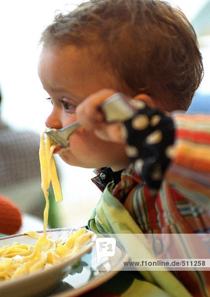 Baby isst Pasta  Seitenansicht.