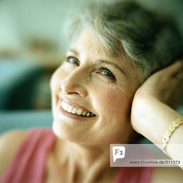 Portrait of mature woman smiling with head resting in hand