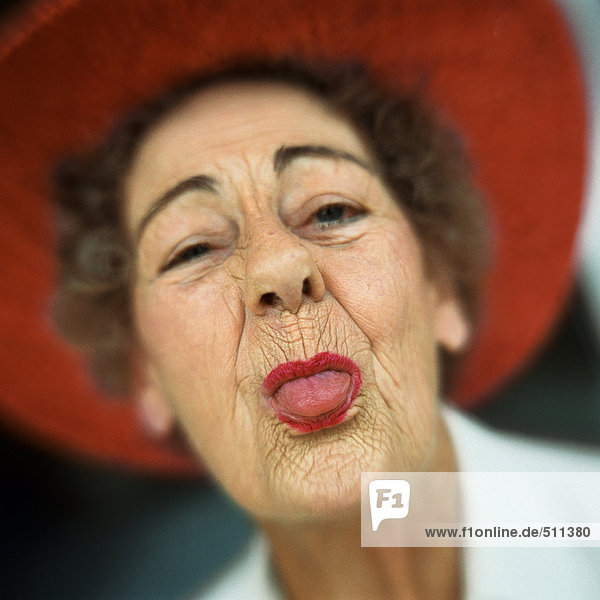Portrait of senior woman wearing red hat with tongue sticking out