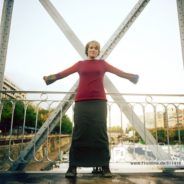 Woman standing on bridge with arms stretched out