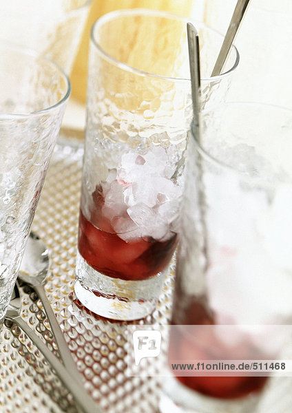 Zwei Gläser halb gefüllt mit rotem Alkohol und zerstoßenem Eis.