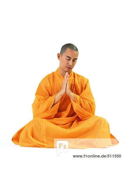 Buddhistischer Mönch sitzend  mit den Händen zusammen meditierend  Vorderansicht