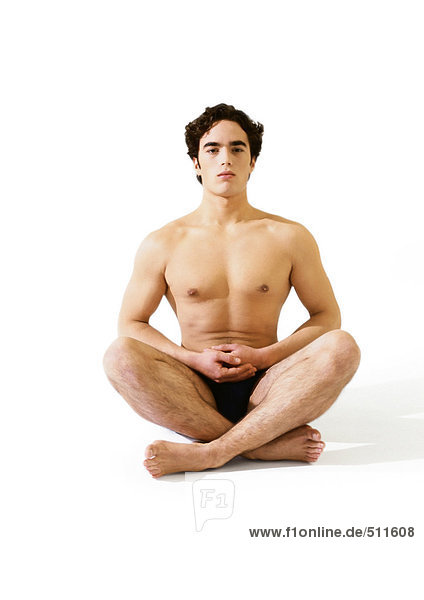 Mann in Unterwäsche sitzend im indischen Stil auf dem Boden mit den Händen zusammen.