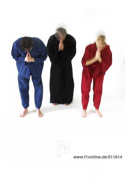 Drei Menschen stehen,  beugen sich mit geschlossenen Händen und Augen nach vorne,  verschwommene Bewegung