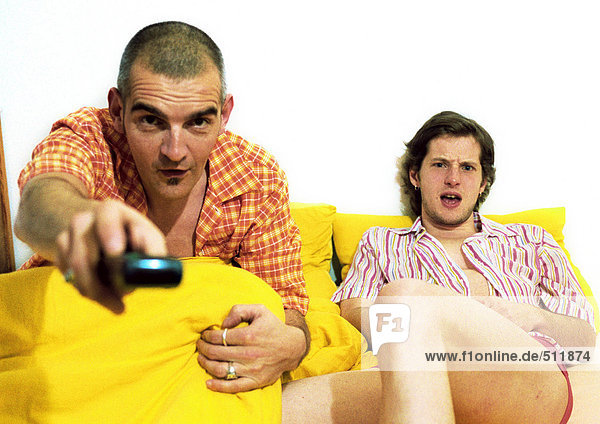 Zwei Männer sitzen auf dem Sofa  ein Mann zeigt auf die Kamera.