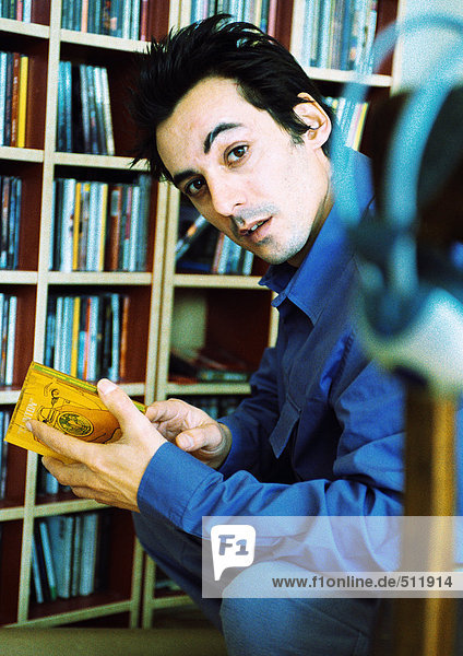 Junger Mann vor der CD-Sammlung  Blick in die Kamera  Porträt.