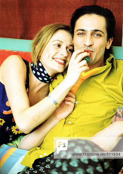 Junges Paar sitzt zusammen  Frauenhand am Mund des Mannes  Porträt.
