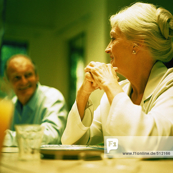 Reife Frau sitzend mit Ellbogen auf dem Tisch  Blick auf den Mann  Blickwinkel niedrig