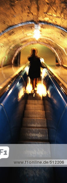 Frau auf Rolltreppe bei Nacht  Rückansicht