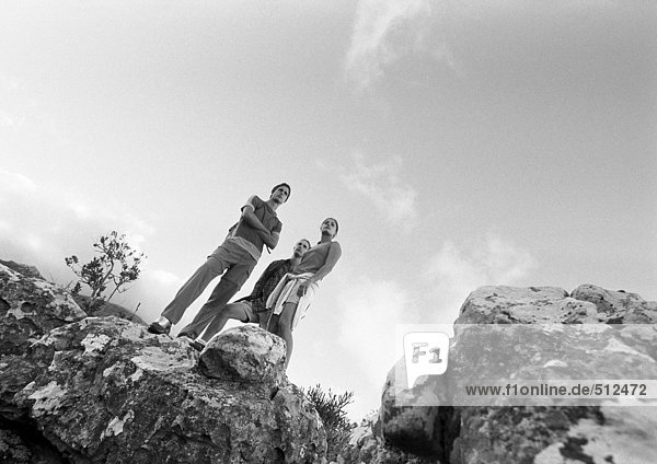 Two young people standing on rocks  low angle view  b&w.