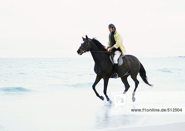 Man riding horse on beach.