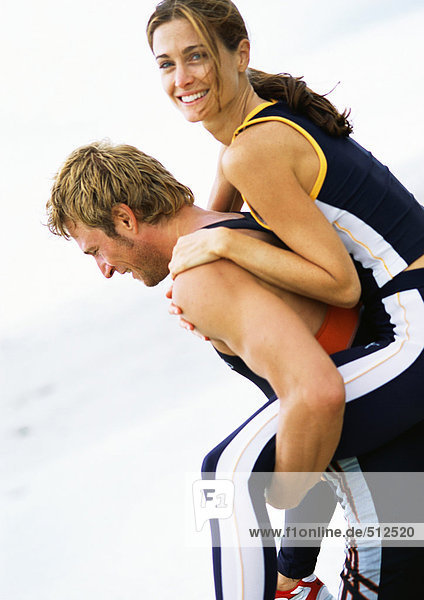 Young couple on beach  woman on man's back.