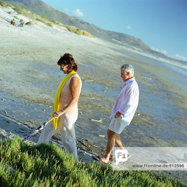 Mature couple walking on beach  side view.