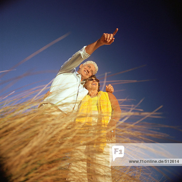 Mature couple standing in tall grass  low angle view