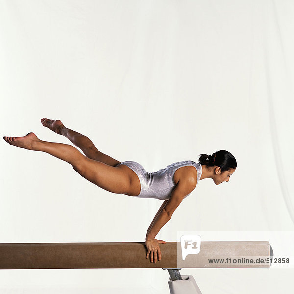 Young female gymnast performing routine on balance beam  side view