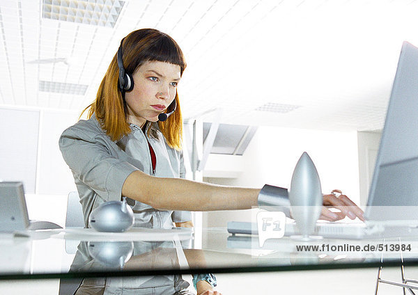 Frau am Schreibtisch mit Headset im Büro
