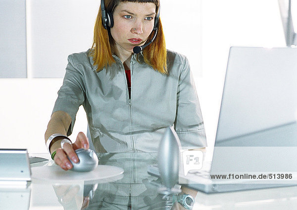 Woman wearing headset using computer