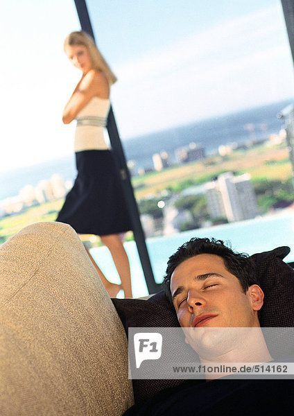 Mann schläft auf Sofa  Frau im Hintergrund