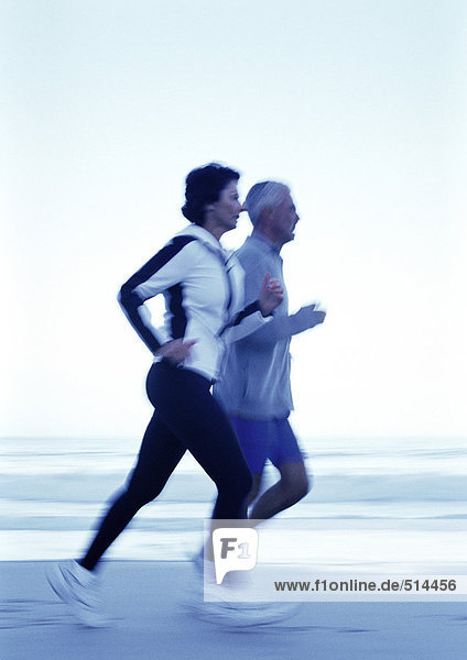 Erwachsener Mann und Frau beim Laufen am Strand  Seitenansicht