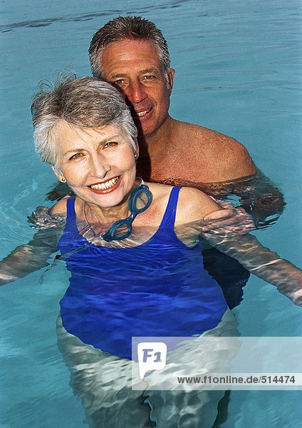 Mature couple in swimming pool  smiling  portrait