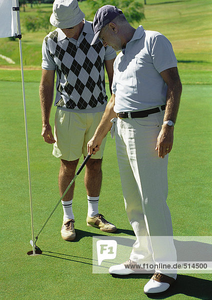 Two mature golfers looking at hole
