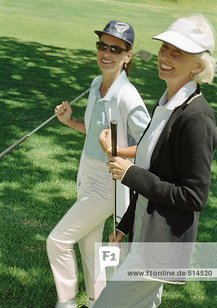 Two mature women with golf clubs  portrait