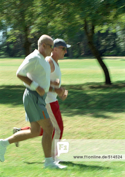 Two mature joggers in park  side view
