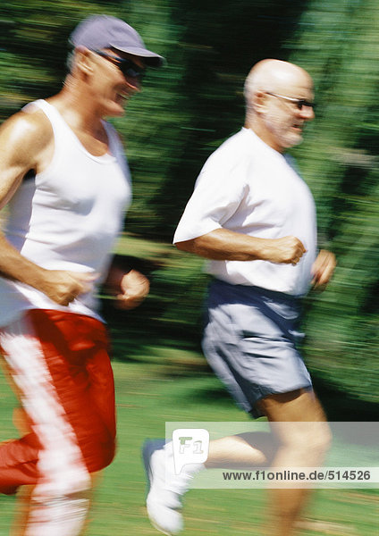 Two mature joggers in park  blurred motion