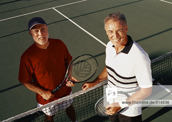 Two mature men on tennis court  portrait