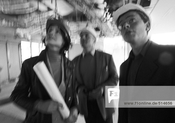 Two men and woman wearing hard hats  blurred  b&w