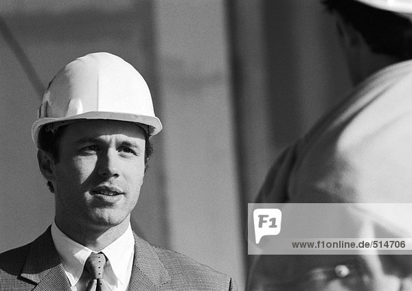 Man in suit wearing hard hat  close-up  b&w