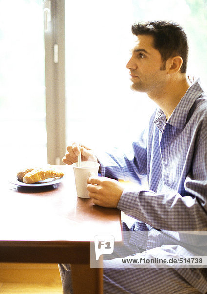 Mann im Pyjama beim Frühstücken