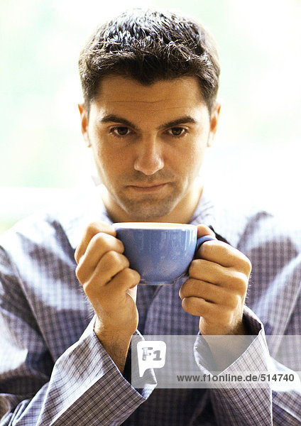 Mann im Pyjama mit Kaffeetasse