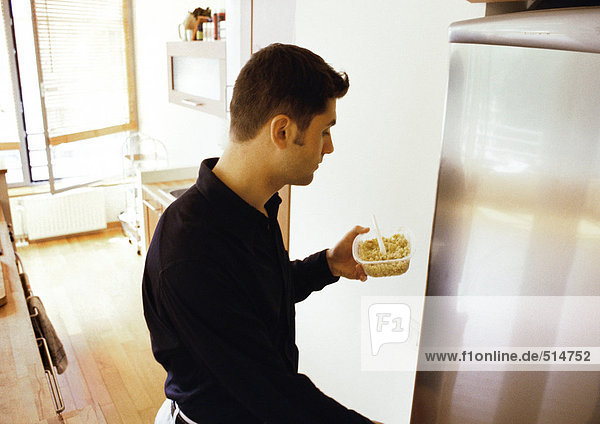 Mann stellt Essen in den Kühlschrank
