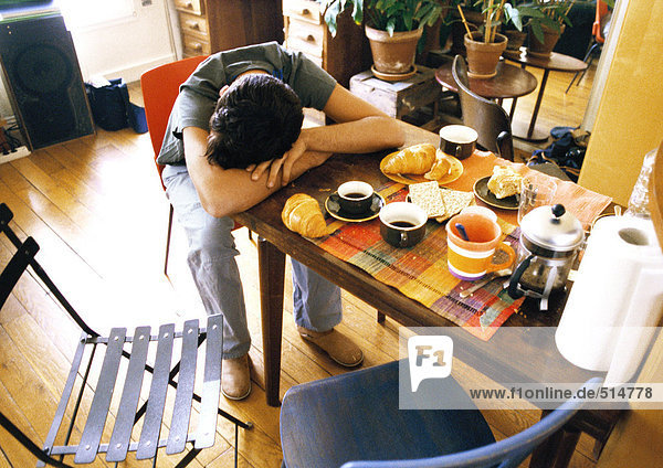 Mann ruht Kopf auf Frühstückstisch