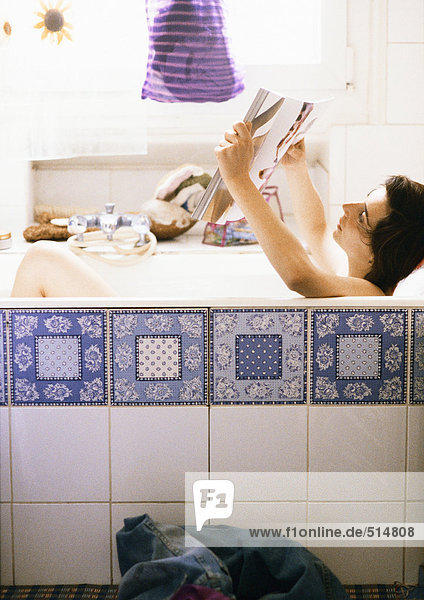 Woman reading in bathtub  side view