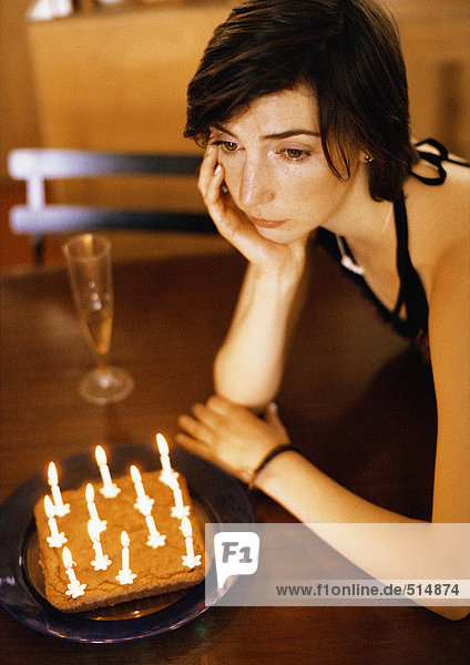 Frau allein am Tisch mit Kuchen und Kerzen