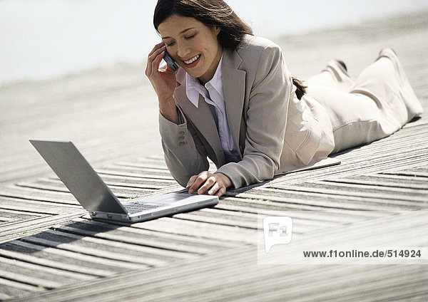 Geschäftsfrau mit Laptop im Freien liegend