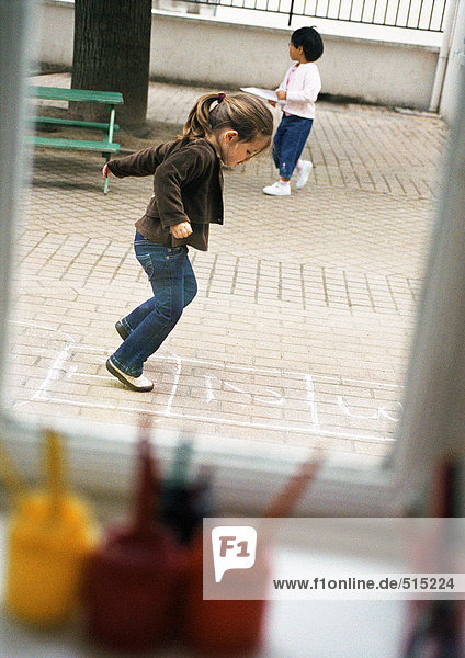 Kinder im Freien  einer spielt Hopscotch  Seitenansicht