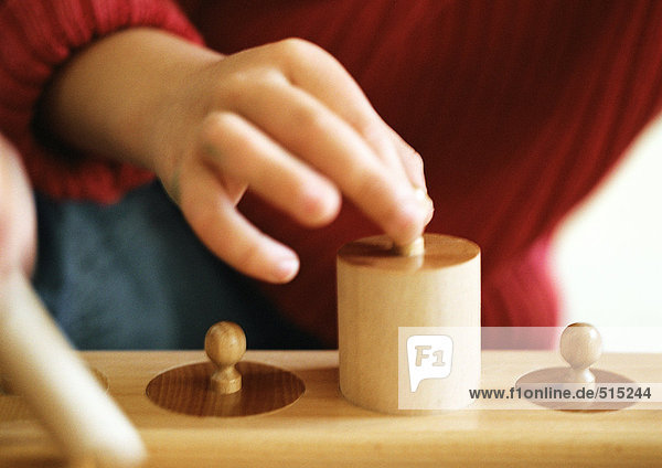 Kinderhand mit Holzgewicht  Nahaufnahme