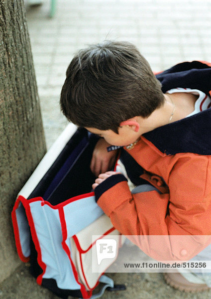 Kind schaut in den Rucksack