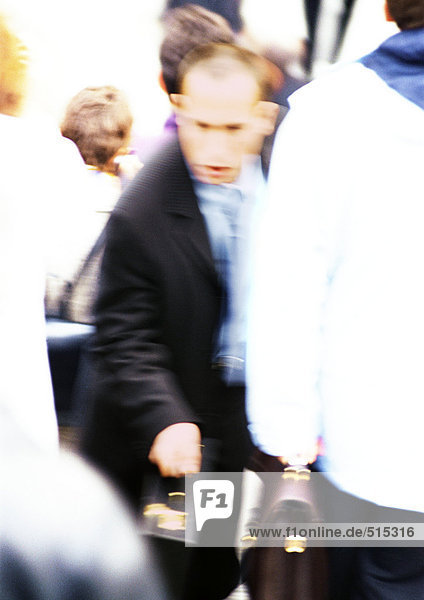 Businessman in crowd with briefcase in hand  blurred