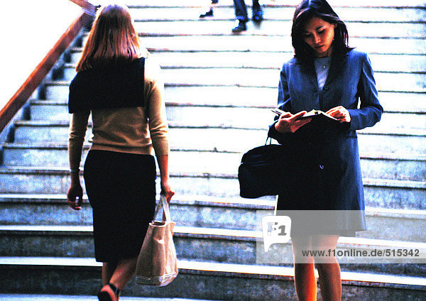 Businesswoman taking notes in front of stairs