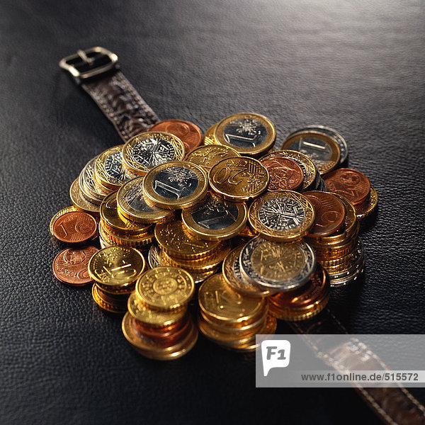 Stapel sortierter Euro-Münzen auf dem Uhrenarmband