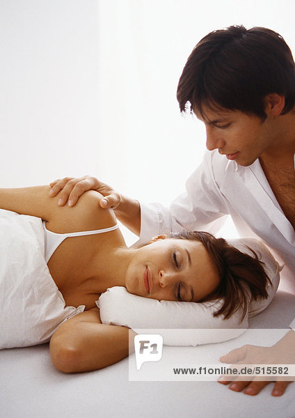 Man touching woman lying in bed.